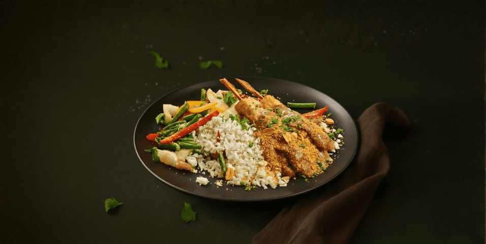 Nasi van bloemkoolrijst met kipspiesjes in authentieke pindasaus