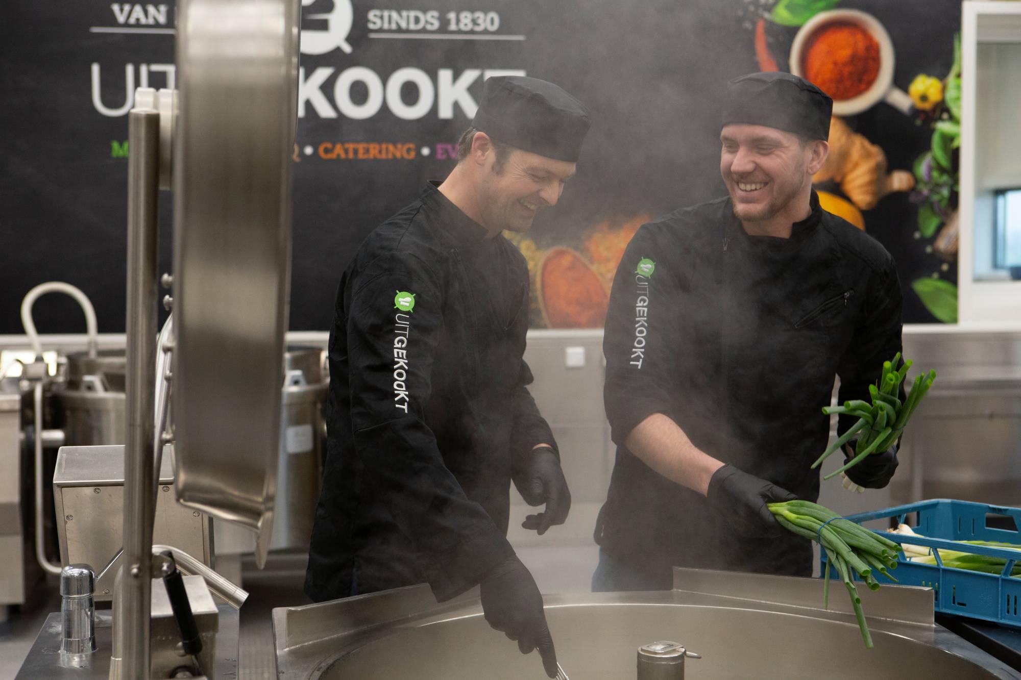 Chefs in de keuken van uitgekookt in een hele grote pan aan het roeren.